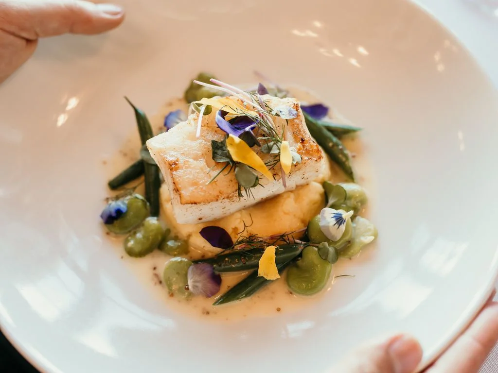 hands holding a place of high end food at the dining room at the oak bay beach hotel