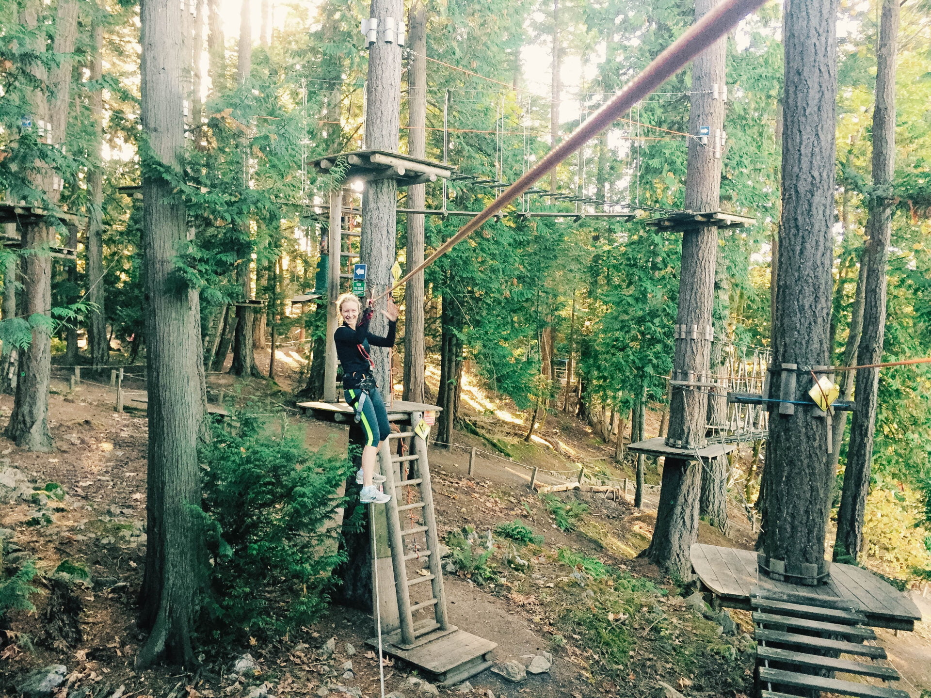 woman balancing on a thin wire in the trees of the wildplay victoria ropes course