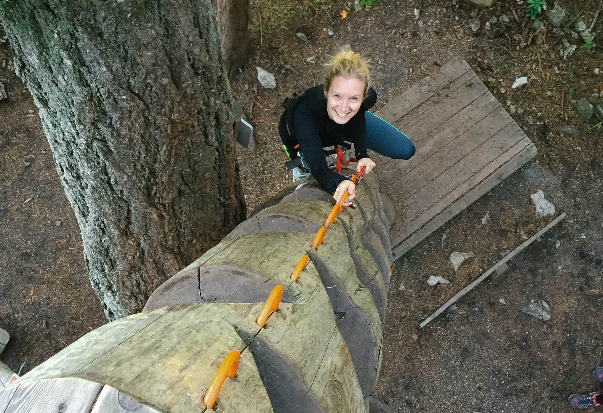 woman climbing up a notched post that has handles at wildplay victoria ropes course