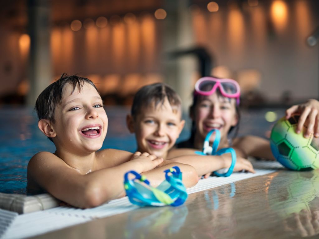 smiling kids hanging on the edge of a pool