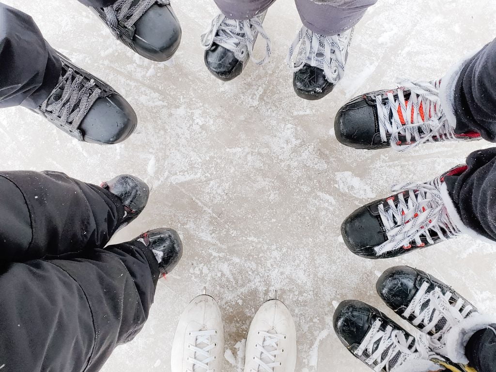 birds eye close up view of peoples feet on the ice wearing skates