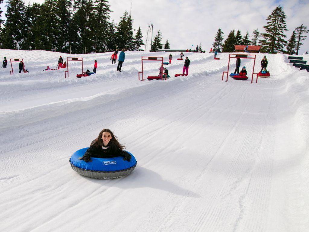 girl on stomach on a tube sledding down a mountain