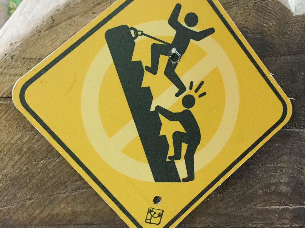 humorous sign of a person kicking someone in the head while on the ropes course 