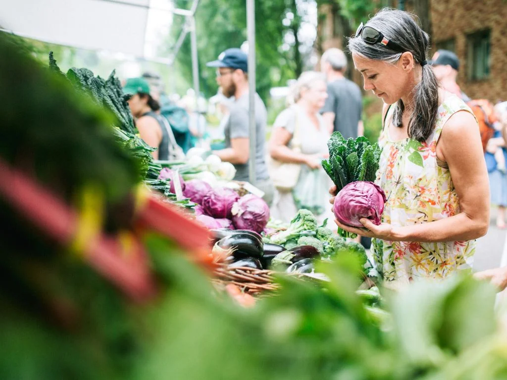 woman holding vegetables at a local farmers market, a fun outing that makes a great Mother’s Day Gifts Vancouver