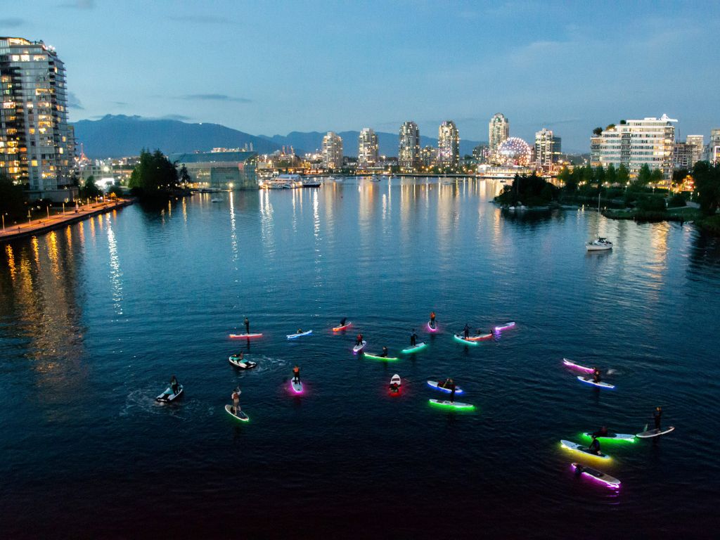 people standing on glowing paddleboards in false creek in vancouver, a fun Mother’s Day Gifts Vancouver