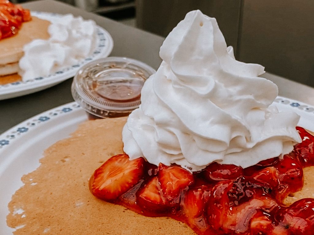 a plate with pancakes covered with strawberries and whipped cream at maan farms