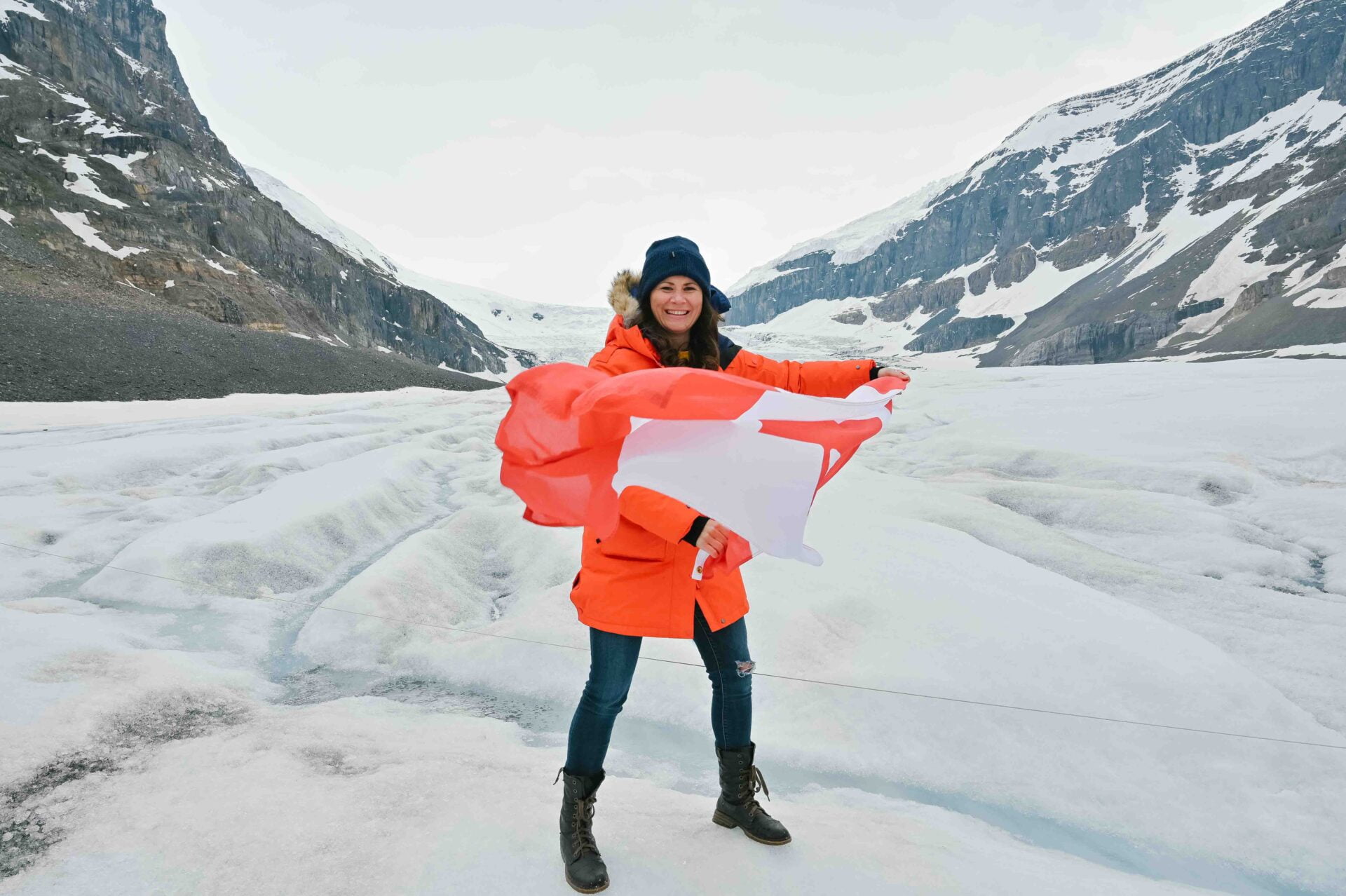 woman waves canadian flag while on an athabasca glacier tour