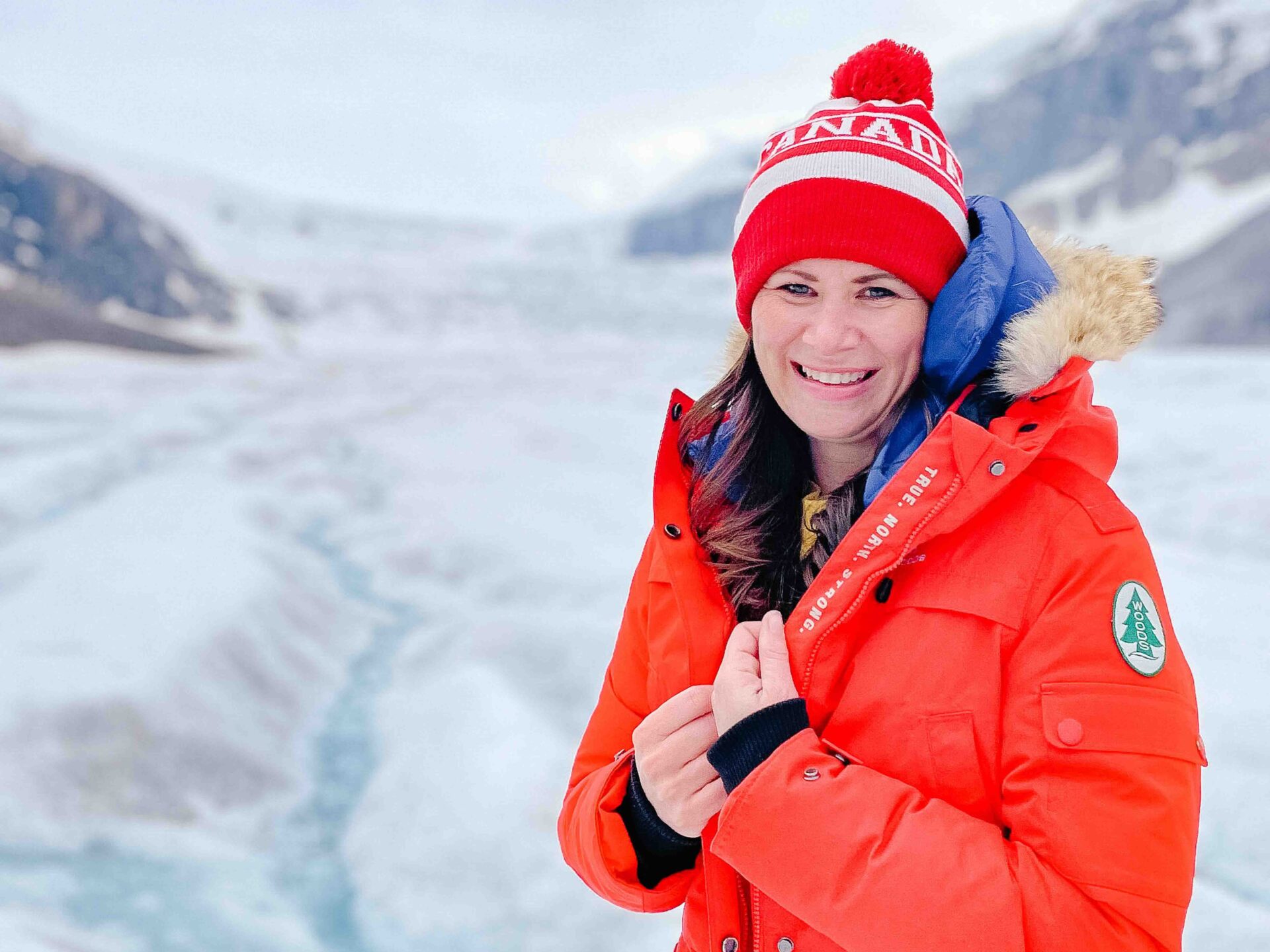 close up photo of a woman bundled in a winter coat and hat while standing on a glacier in the rocky mountains
