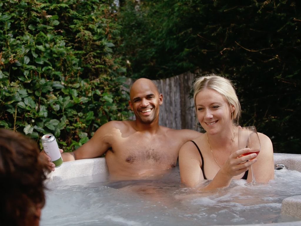 man and woman sitting happily in a private hot tub with their child at the tofino family resort