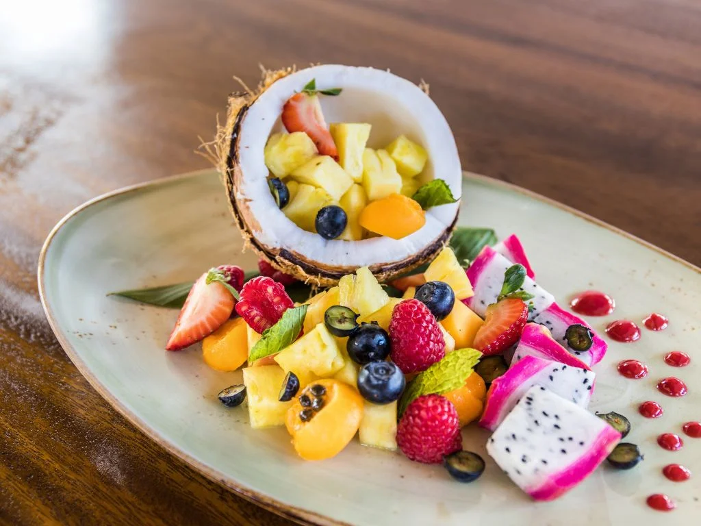 gorgeous fruit spilling out of half a coconut on a plate at the restaurant at koloa landing resort, the best family hotel in kauai