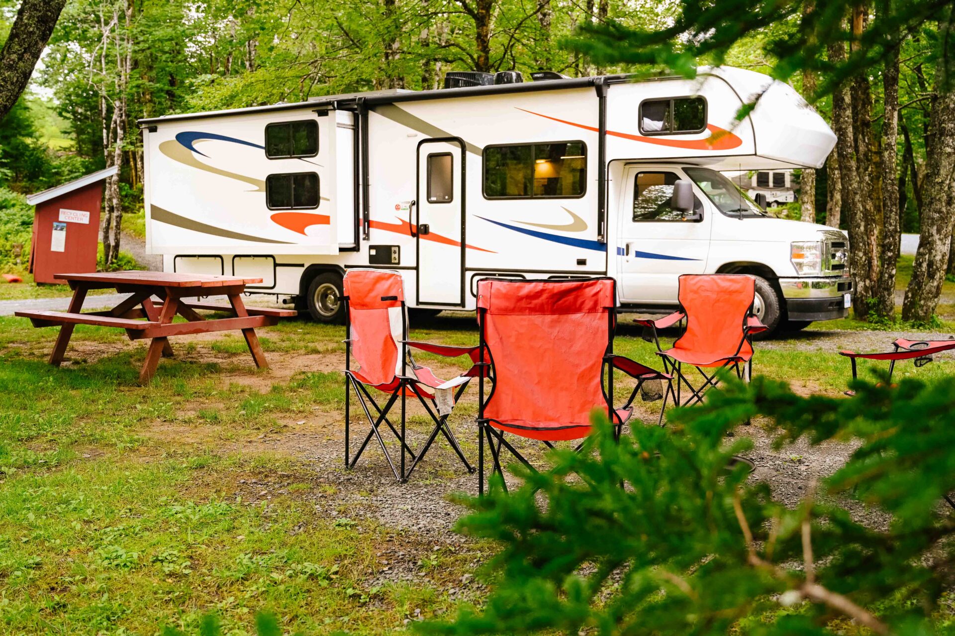 a large canadream rv sits parked in a forested campsite