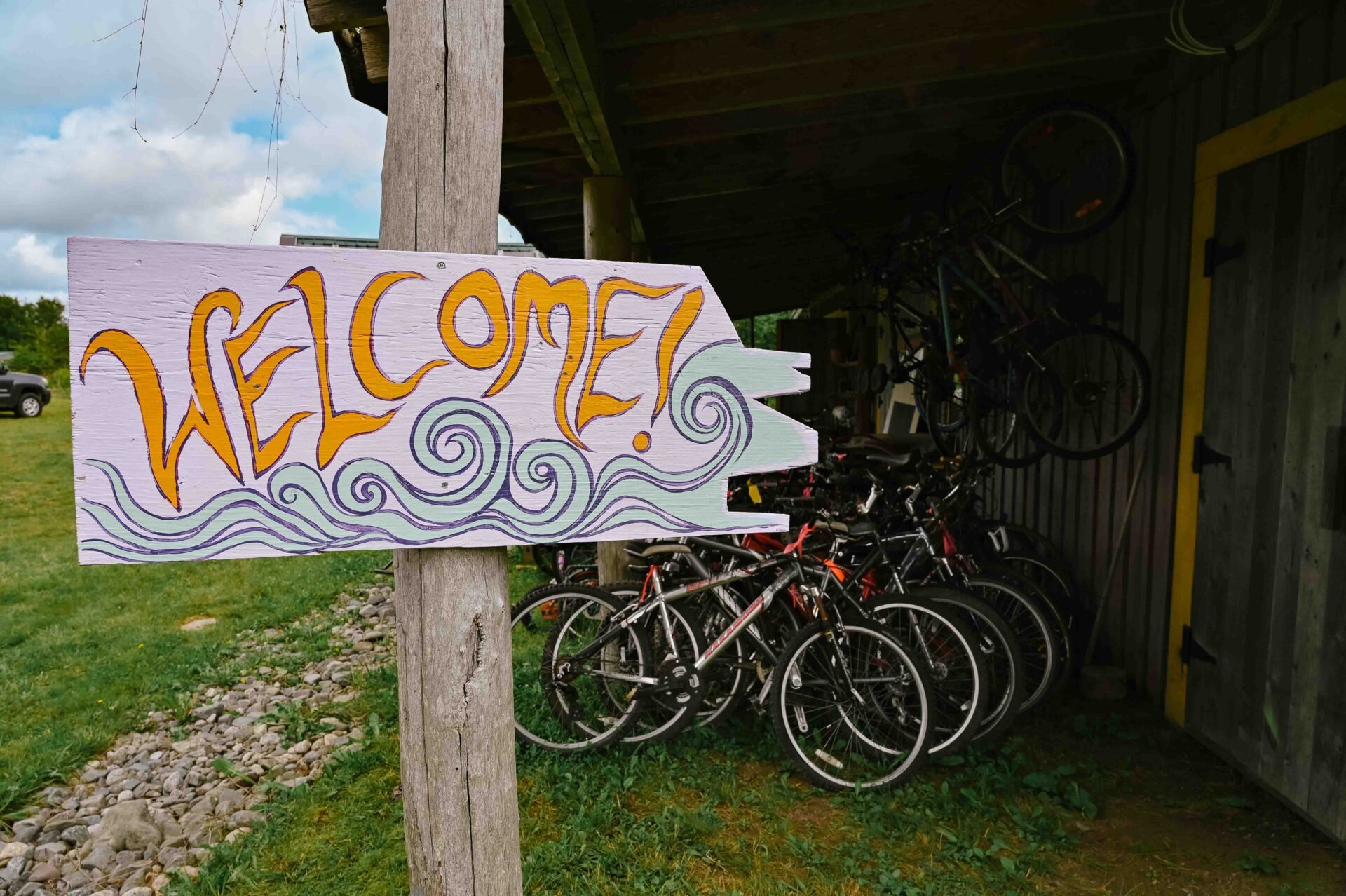 a welcome sign sits outside a building with a variety of rental bikes in the background