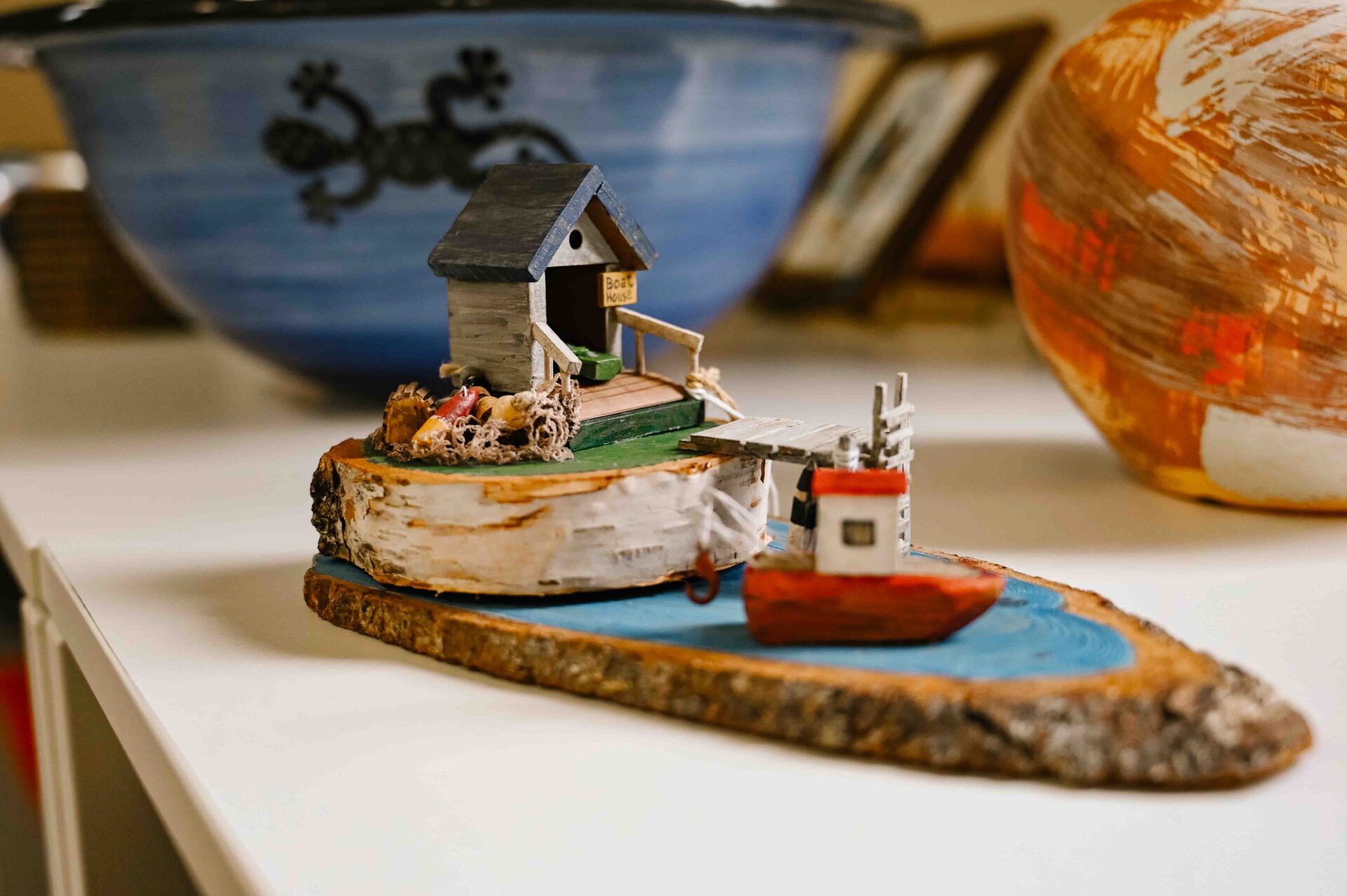 close up of a small handmade wooden souvenir of a boat house and a fishing boat