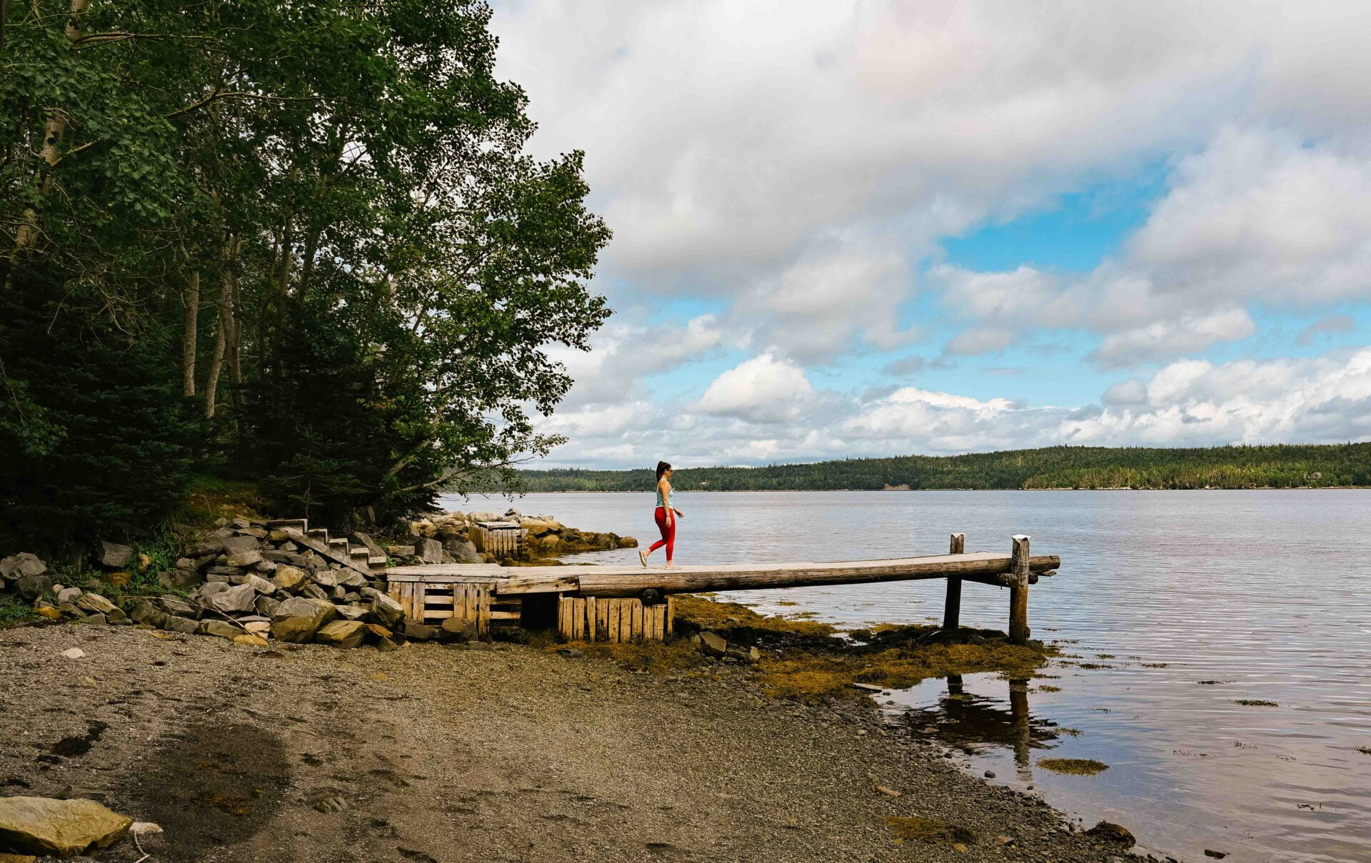 woman walking out on an old small pier on one of the 100 wild islands in nova scotia