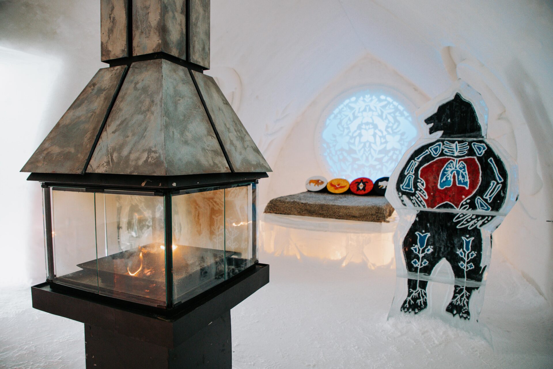 inside a themed room with bear ice sculpture and fireplace at the Hôtel de Glace