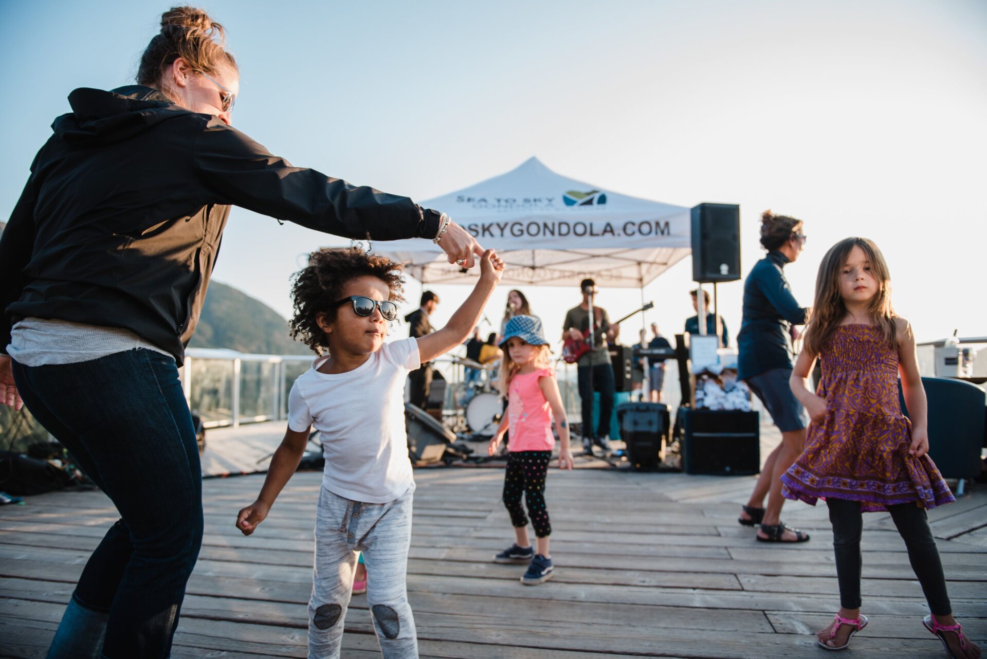 adults and kids dancing to the live music that is being played by a band at the sea to sky gondola music series