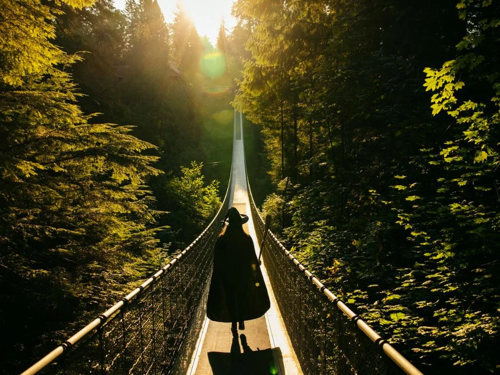 a person dressed as a witch walks across the capilano suspension bridge