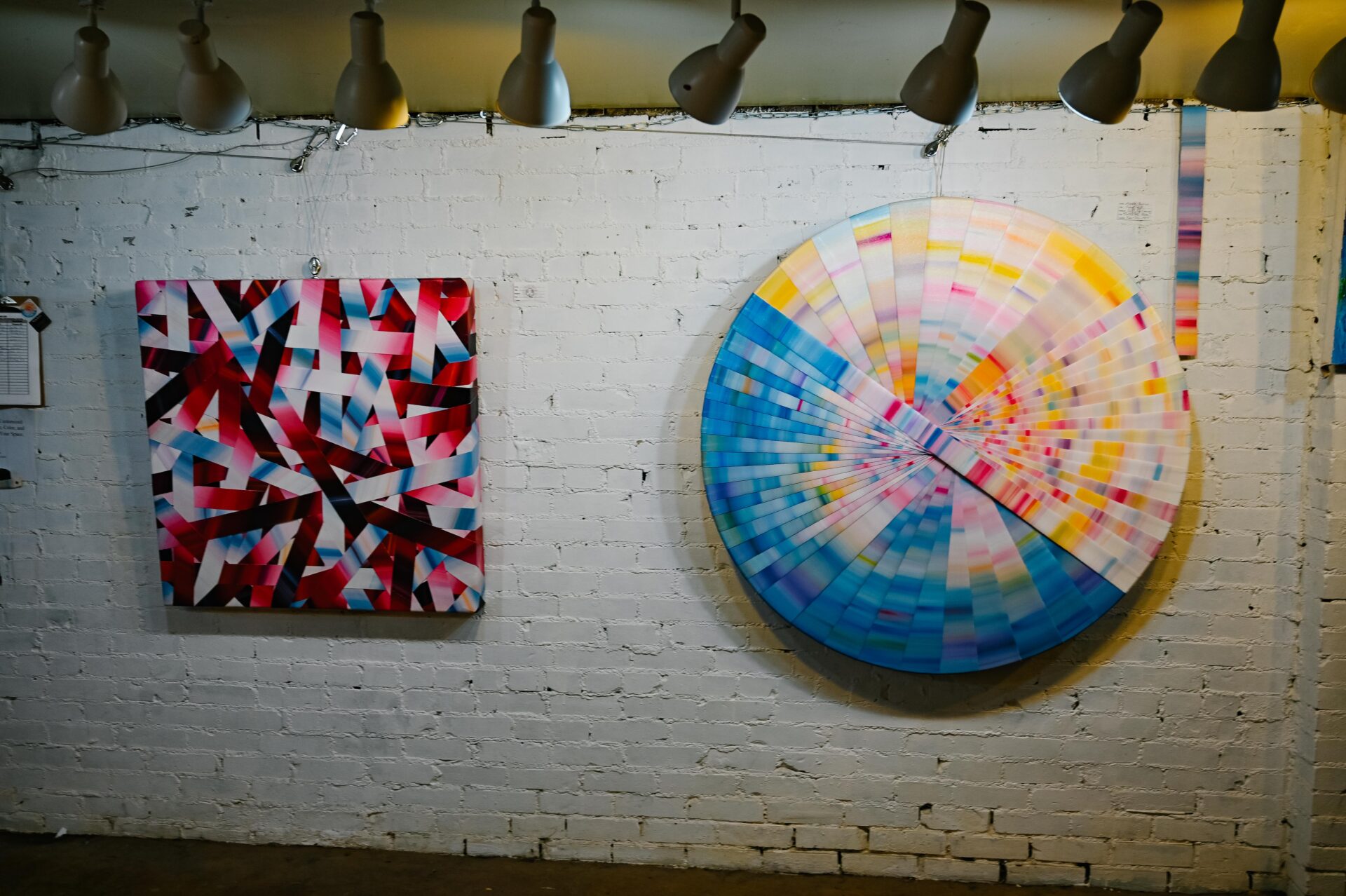 two canvas colourful paintings hanging on the wall downstairs at the Denver Art Society underground studios