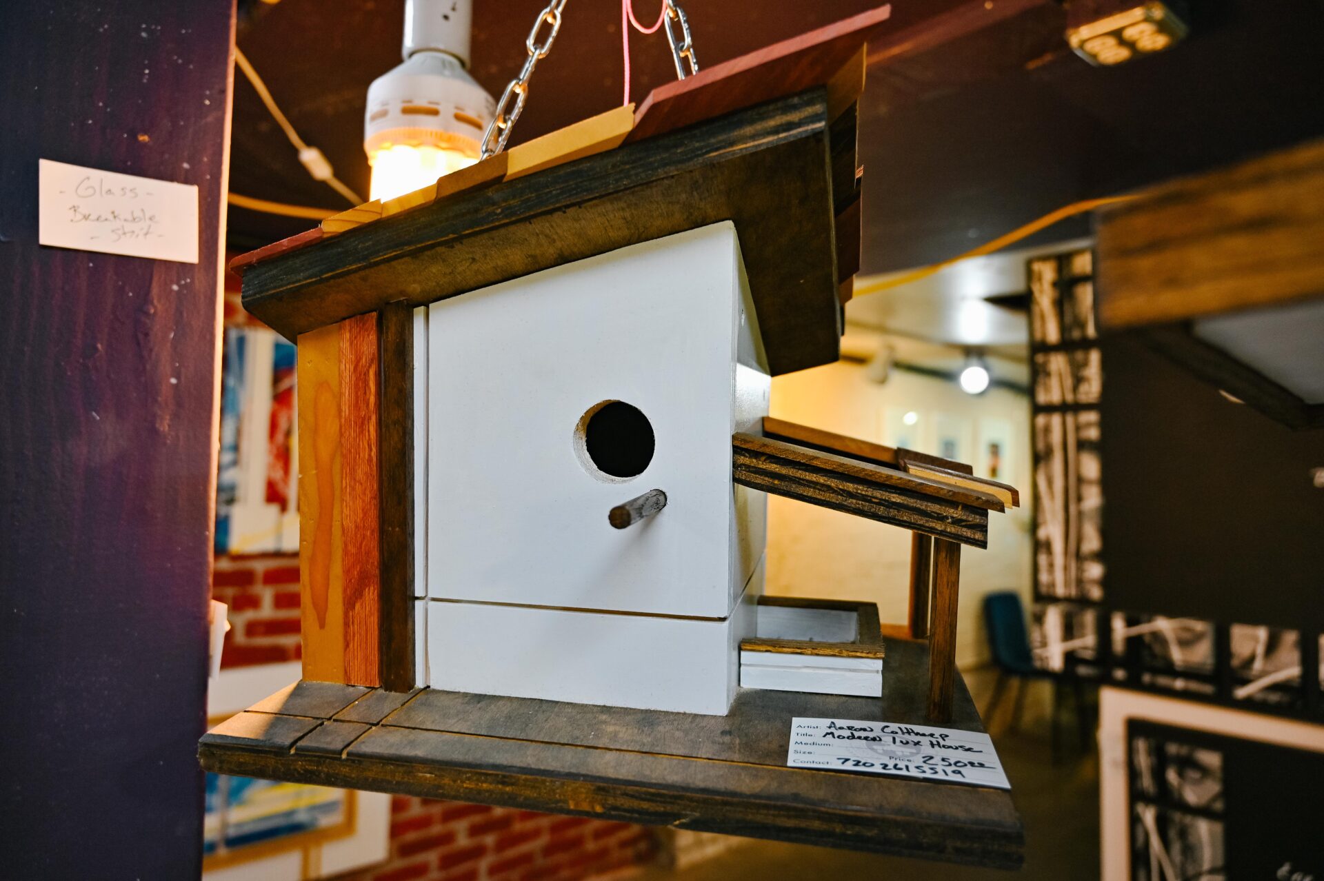 a wooden birdhouse hangs on display