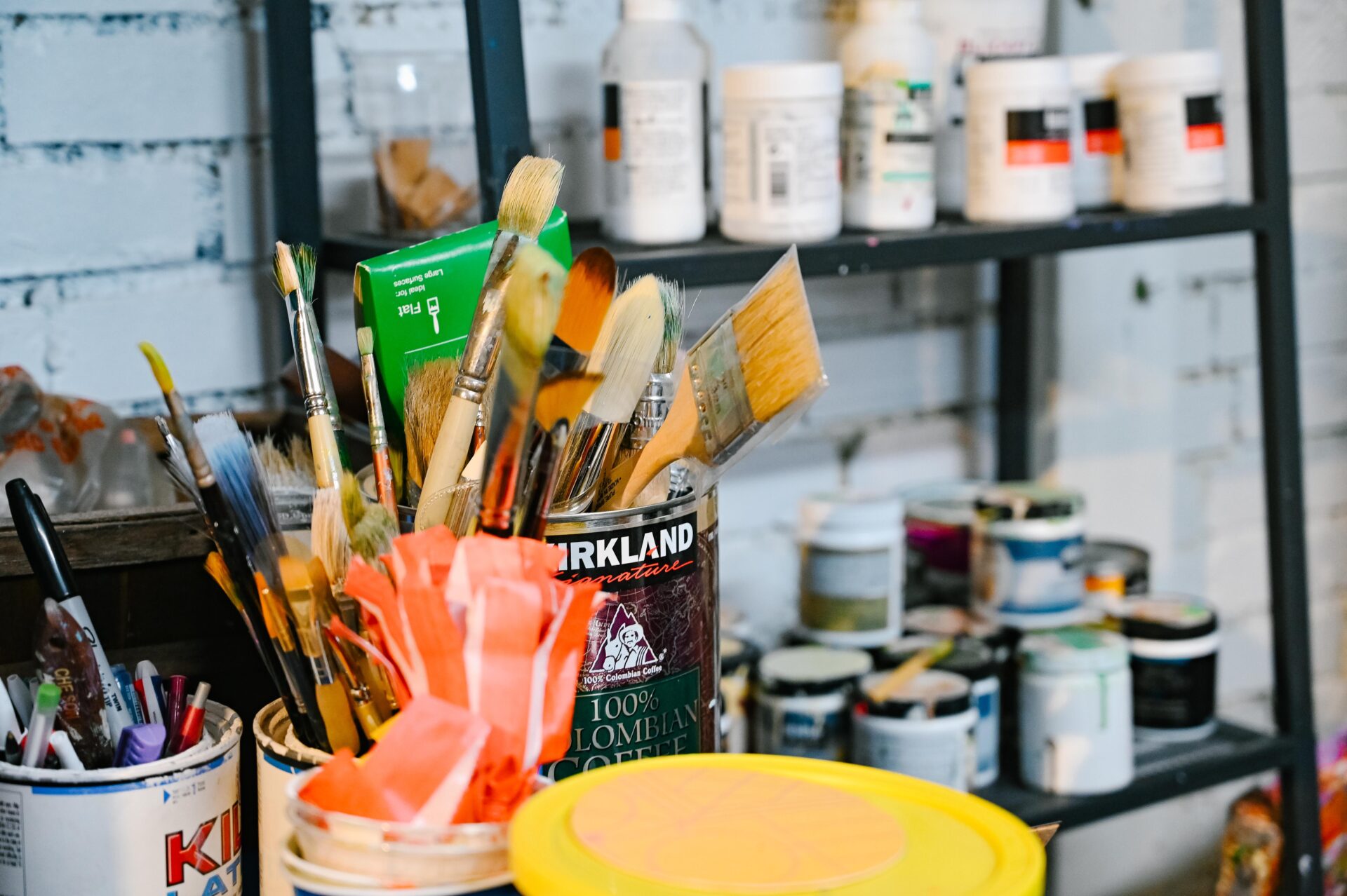 close up of paint brushes and various other art supplies