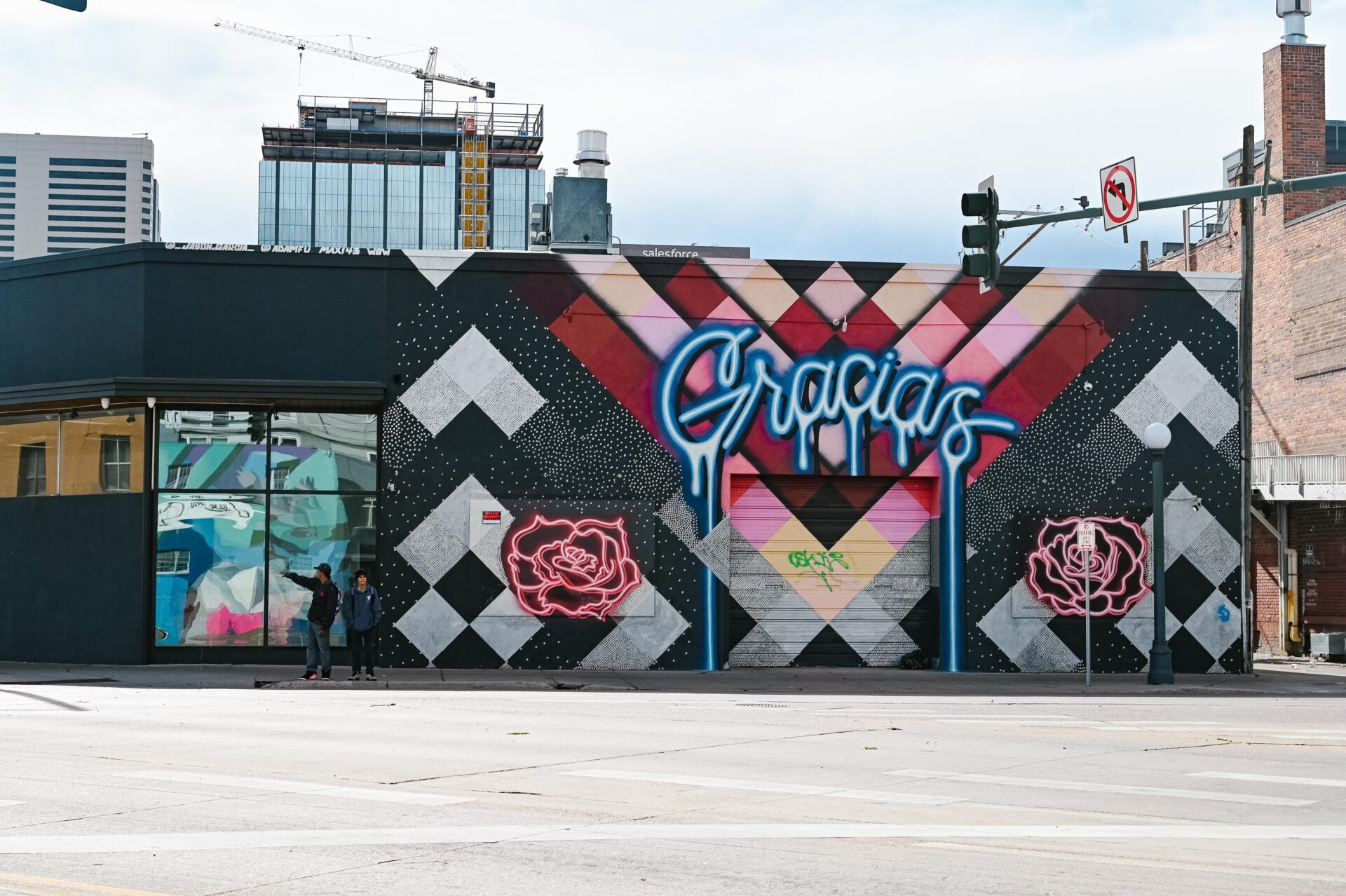 large mural with the word Gracias, two large roses and a square pattern in the background