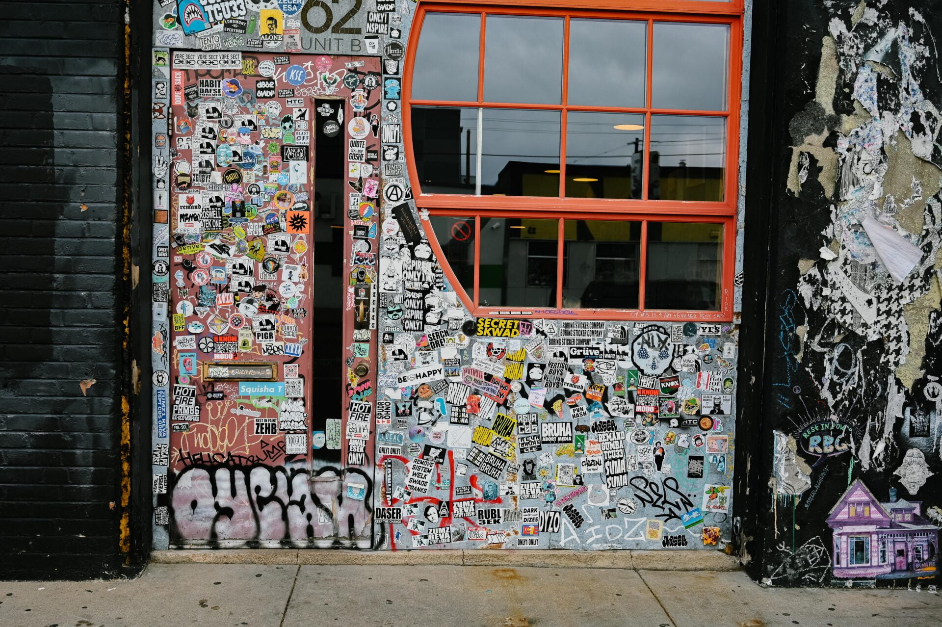 a door and wall covered in stickers that were made and designed by a variety of street artists, seen on the denver graffiti tour