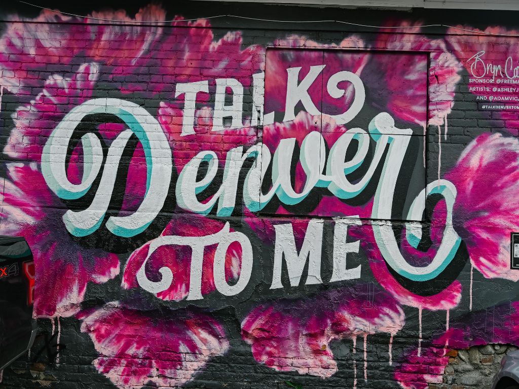 mural of pink flowers with the text, Talk Denver to Me, in the middle