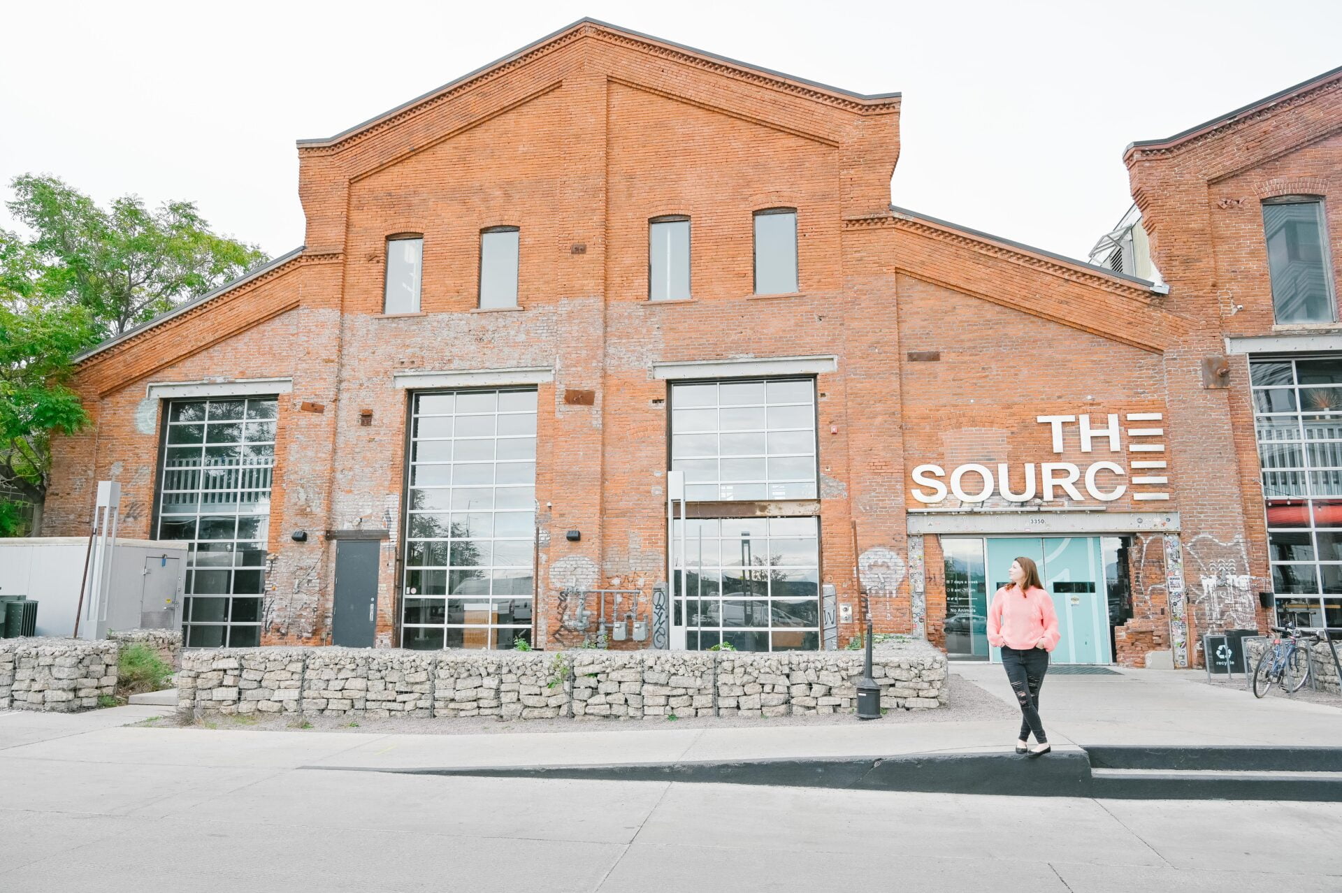woman standing outside the market hall building at The Source Hotel Denver 