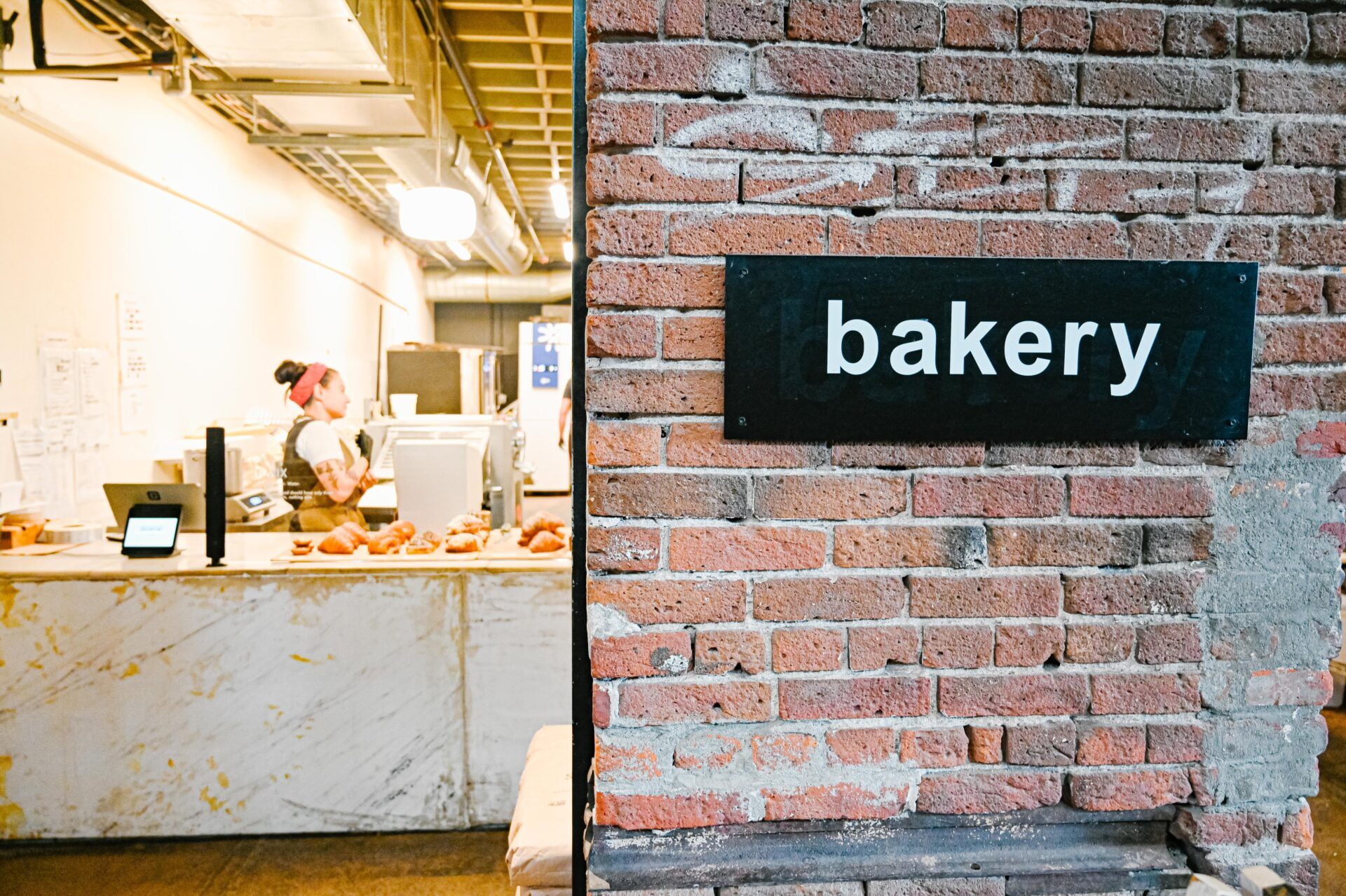 a woman working behind the counter at reunion bread at the source market hall