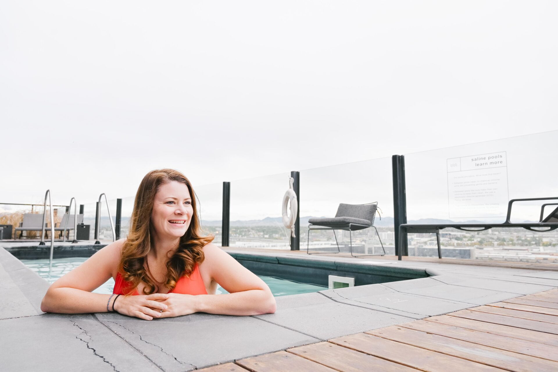a woman stands in the rooftop pool looking off towards the distance