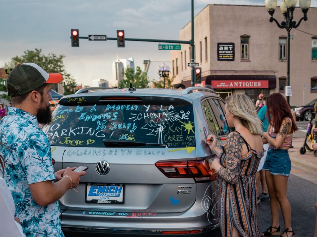 people on the street decorating a mini van with paint markers during one of the santa fe art districts first friday nights