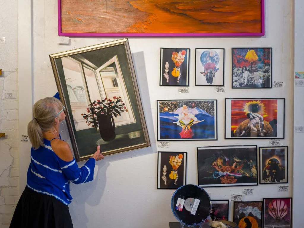 an artist hanging up her work on the wall inside the Denver Art Society gallery