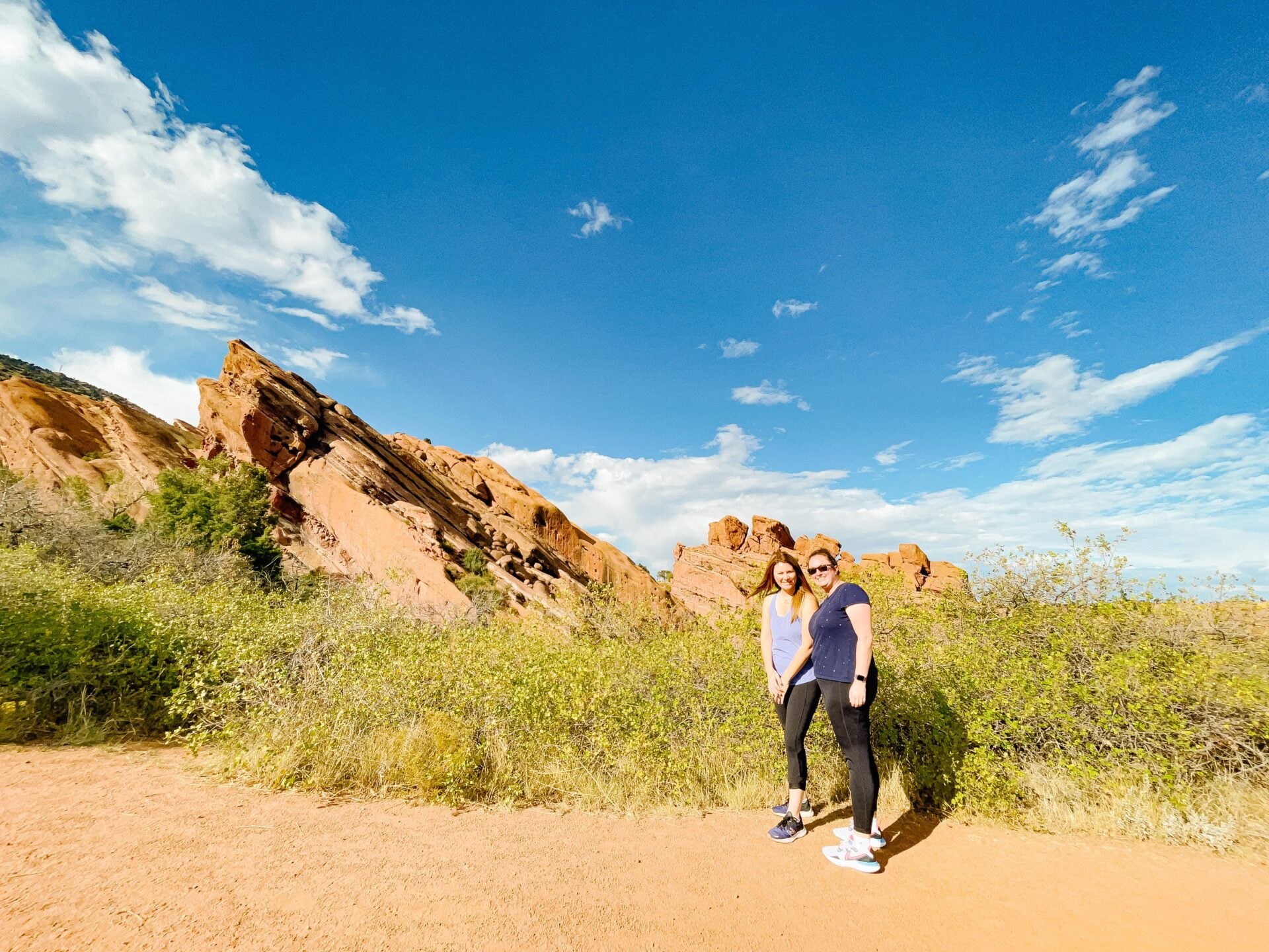 two woman standing in front of rocks inside red rocks park