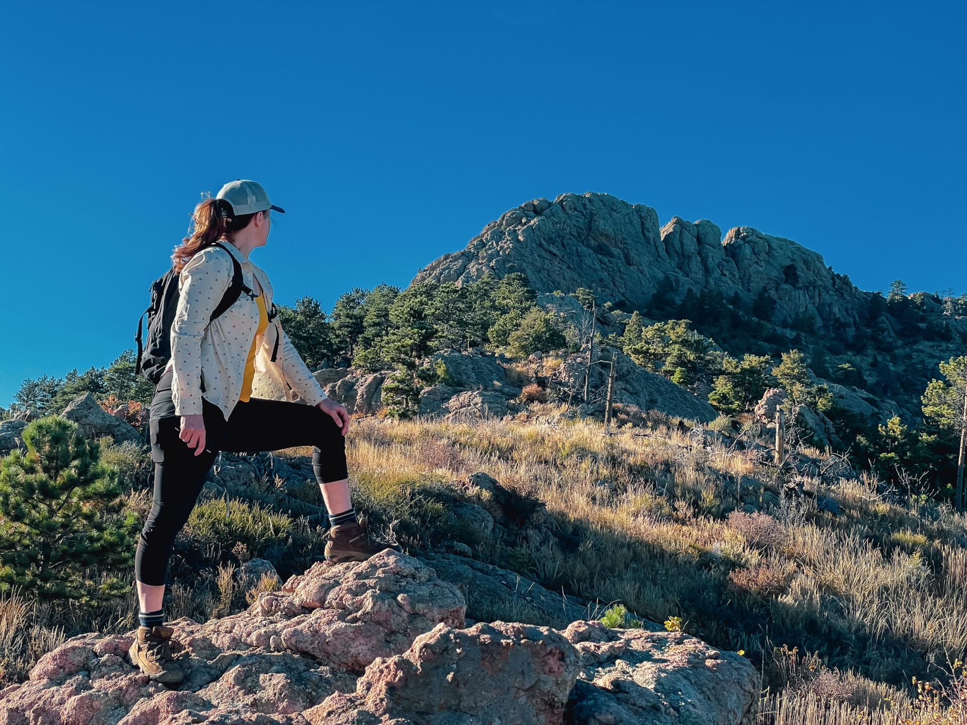 woman stands at the base of horsetooth mountain looking up at the summit