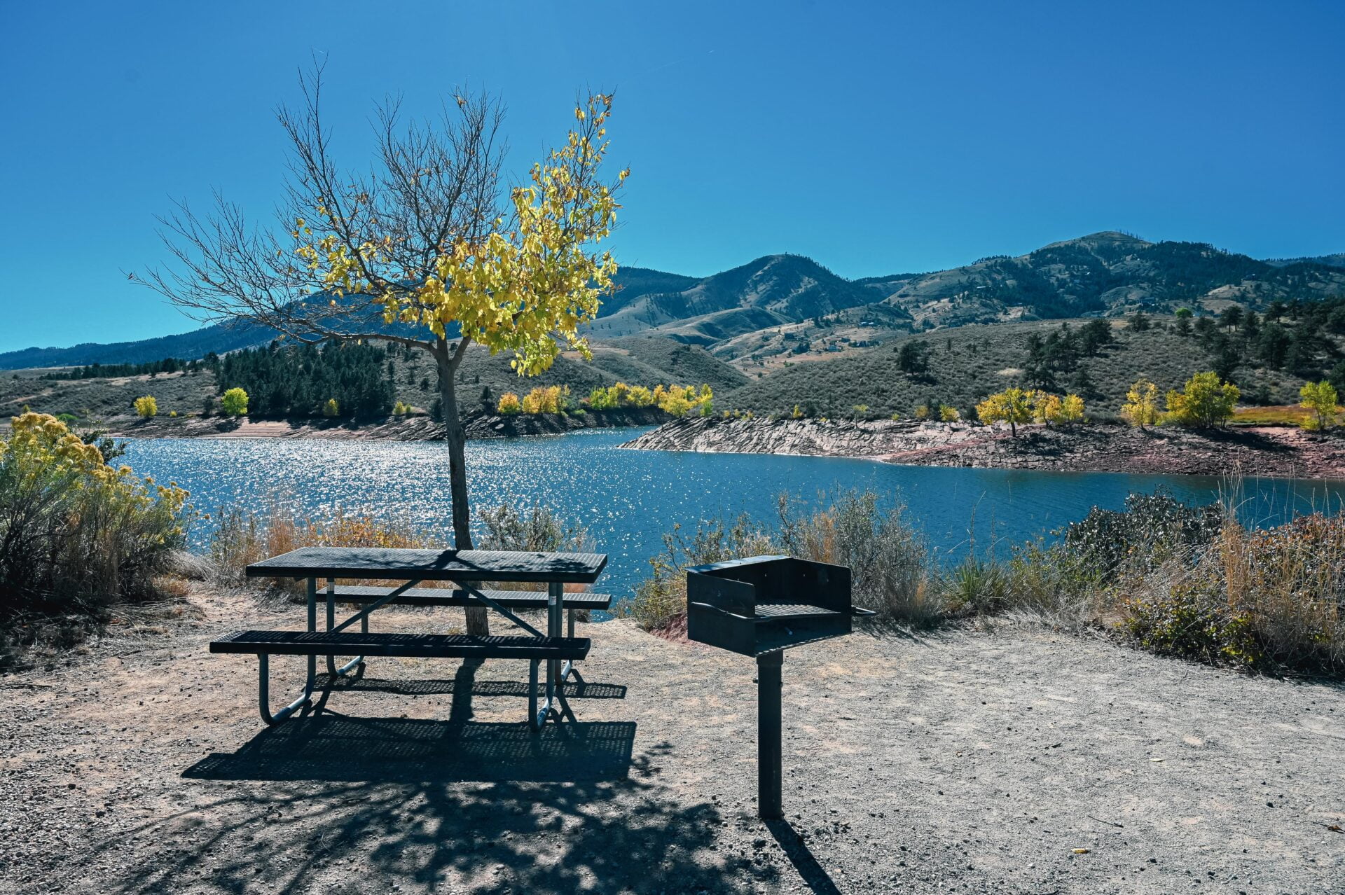 view of the horsetooth reservoir looking past a picnic table and bbq