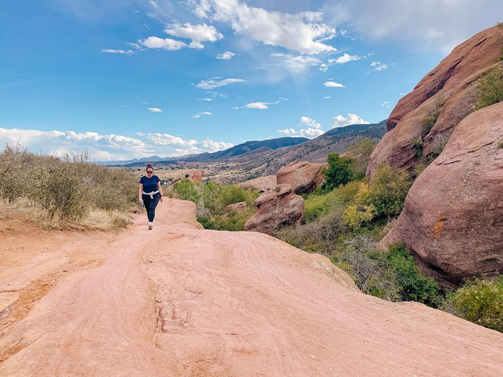 woman hiking up smooth red rock formations at red rocks park on a northern colorado road trip