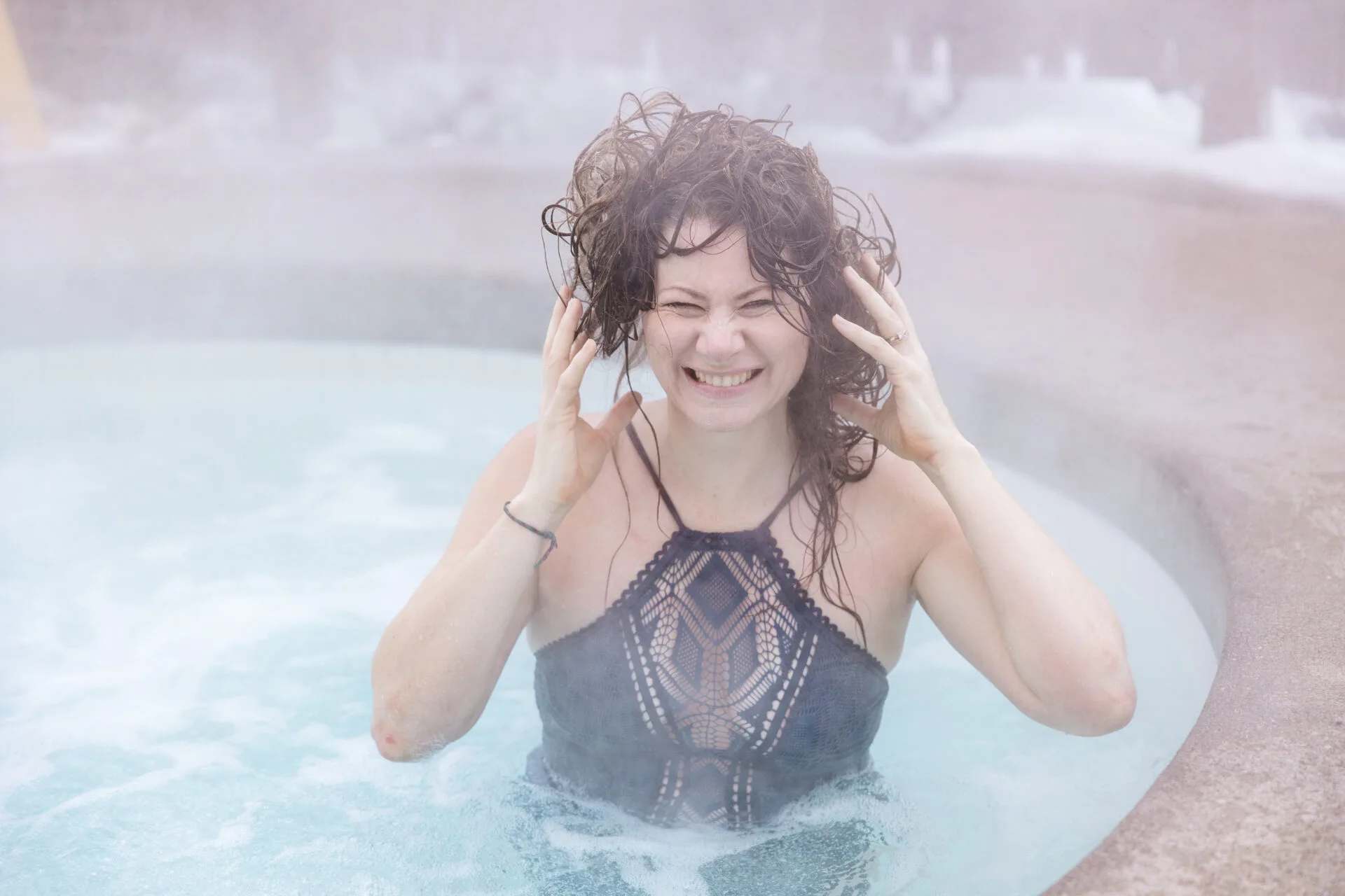 a woman stands in a hot tub at scandinave spa, her hair is frozen in the cold winter air