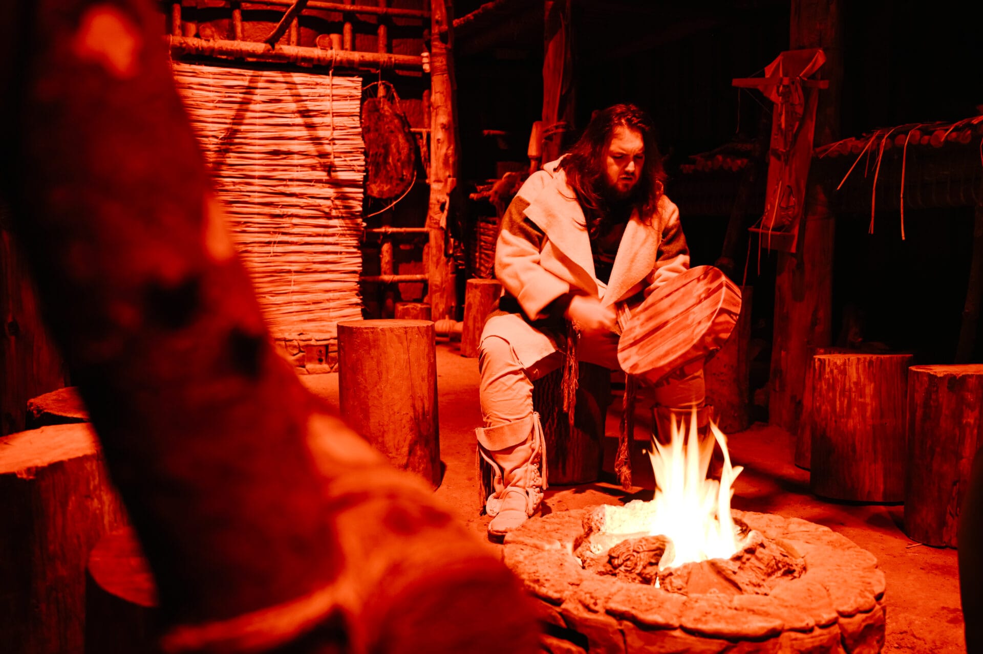 indigenous drummer and storyteller inside a traditional longhouse