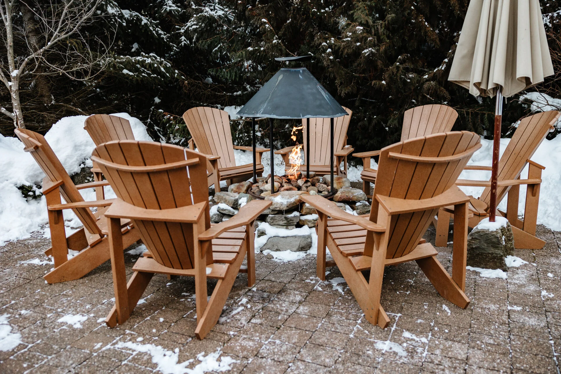 a fireplace surrounded by 8 brown wooden chairs outside at the scandinave spa in whistler