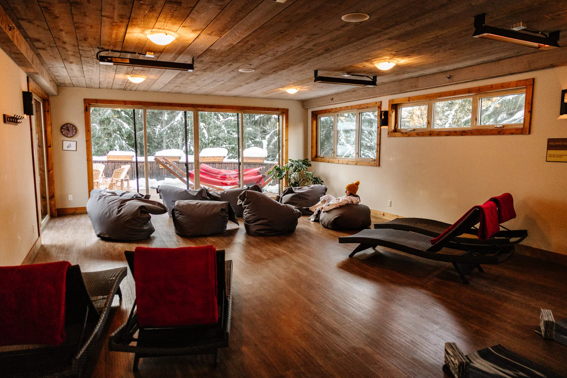 a person wearing a yellow toque relaxes in a room filled with bean bags, lounge chairs and yoga mats at scandinave spa in whistler