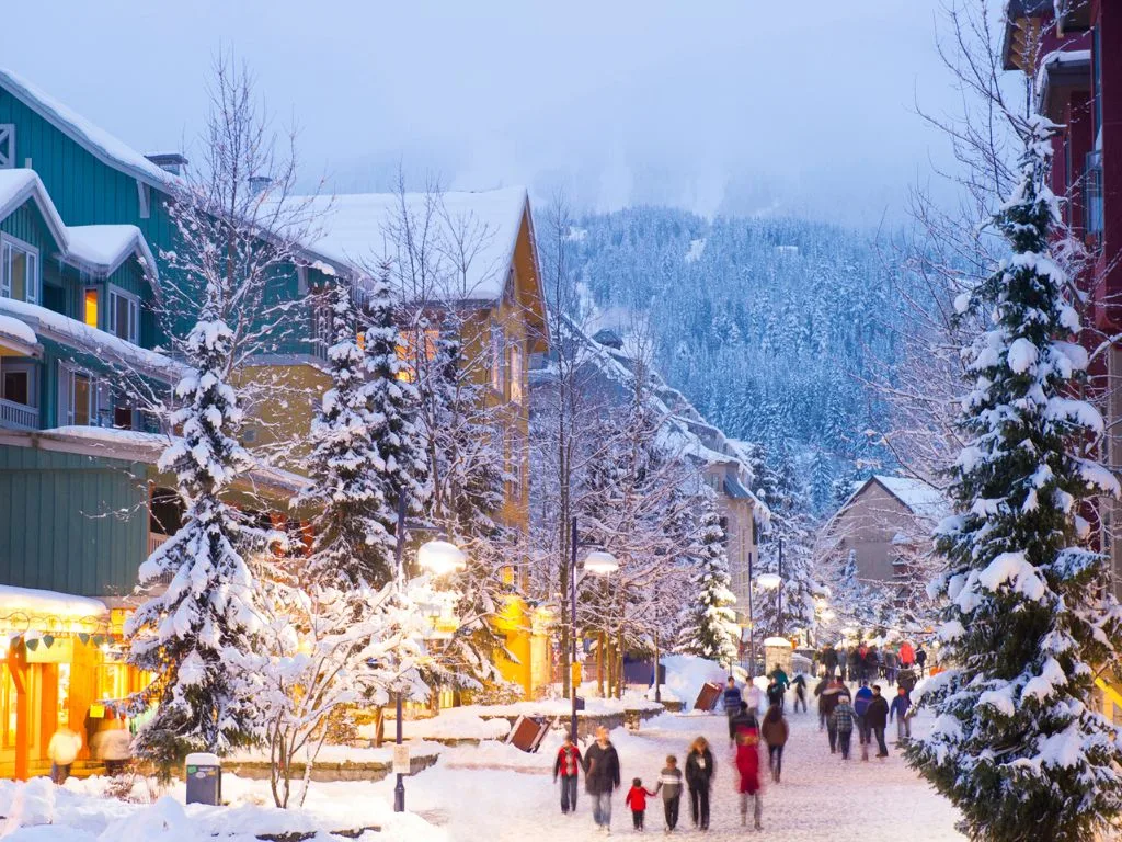 people walking through whistler village during the winter with snow