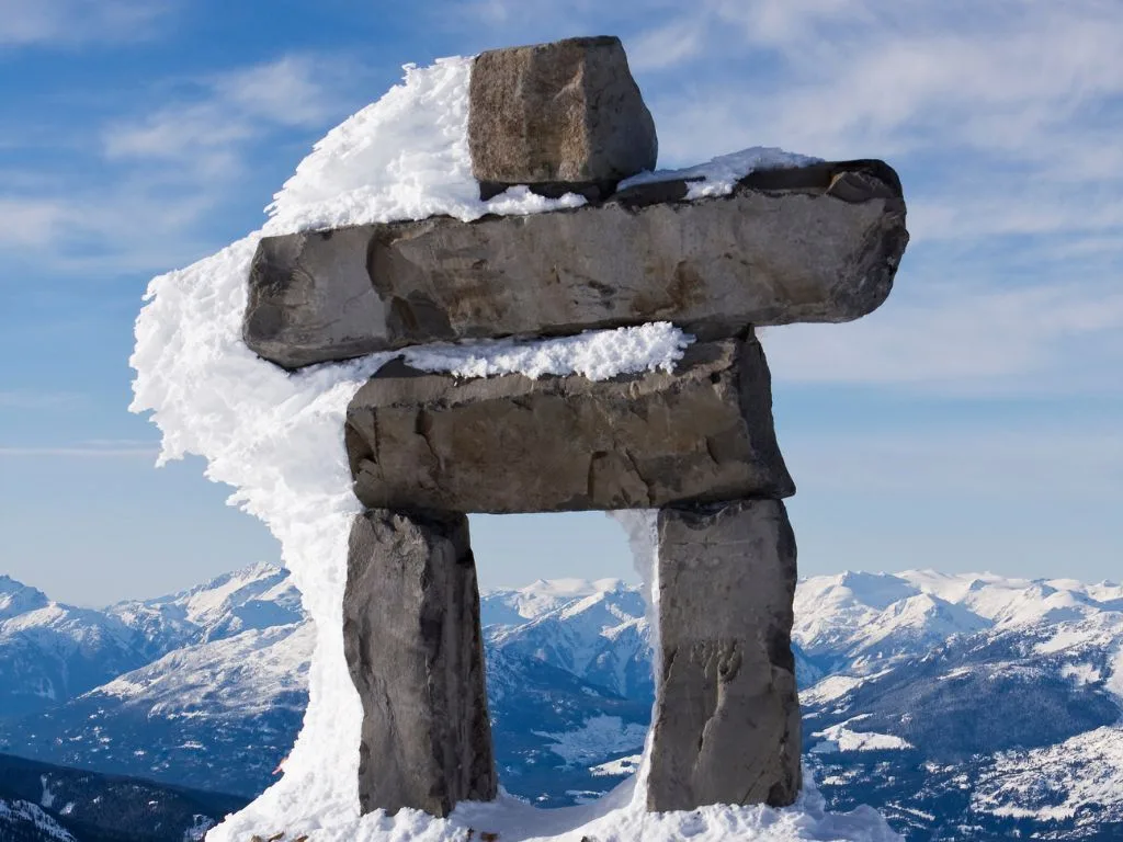 a large rock inukshuk covered with snow in whistler