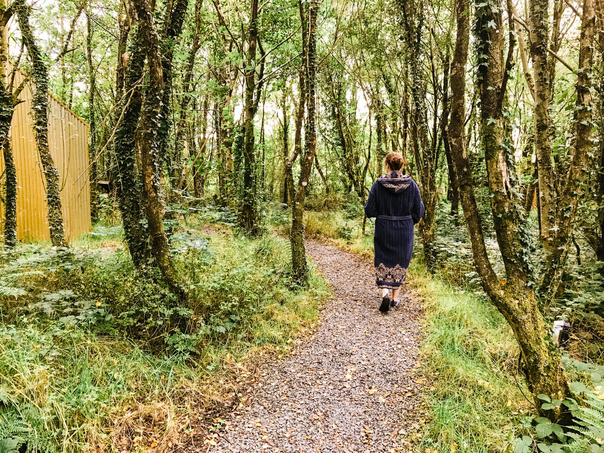 woman walks through the forested trail at the spa experience at finn lough in ireland