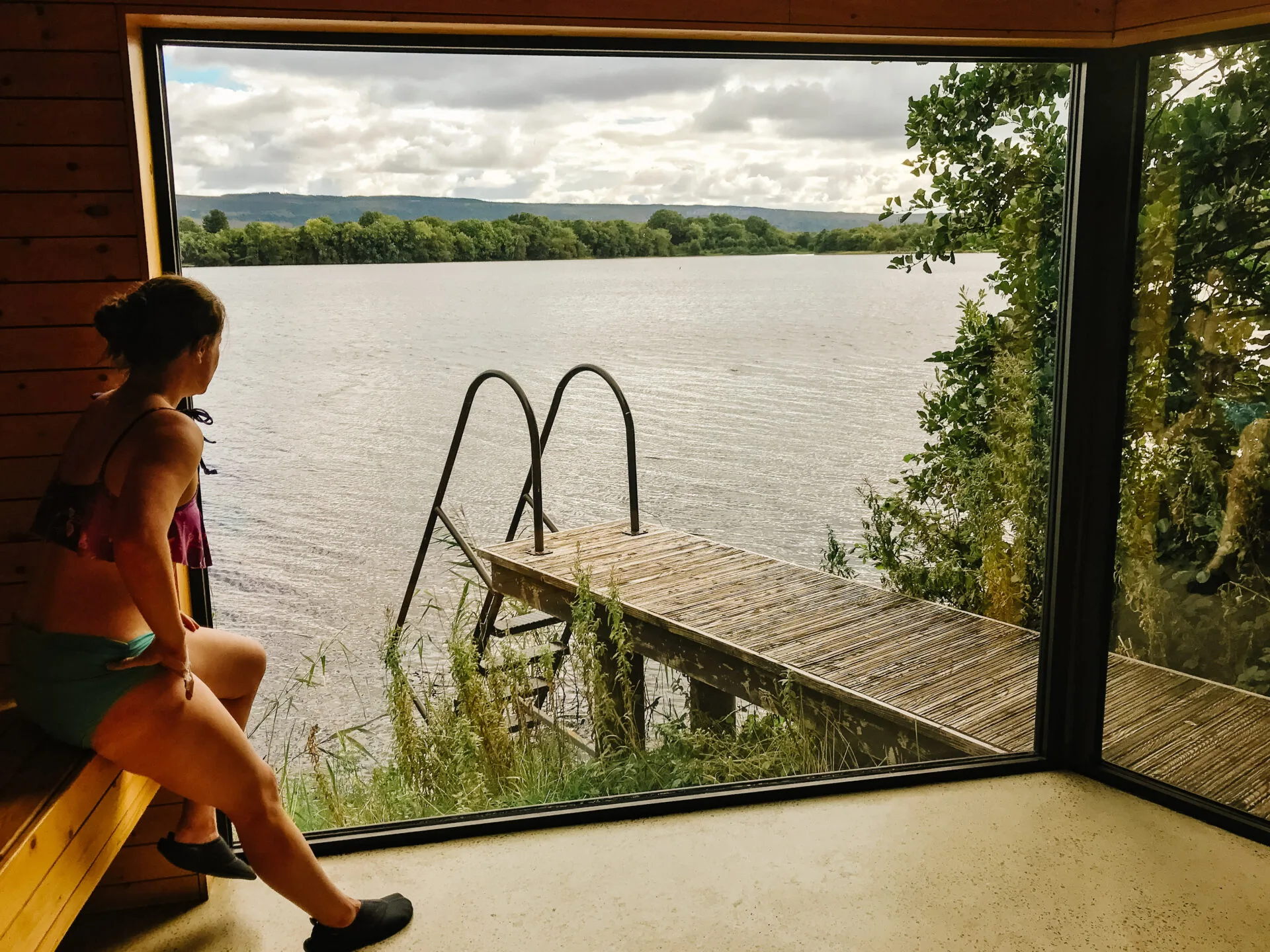 woman looks out over the lake while sitting inside a sauna at the spa at finn lough
