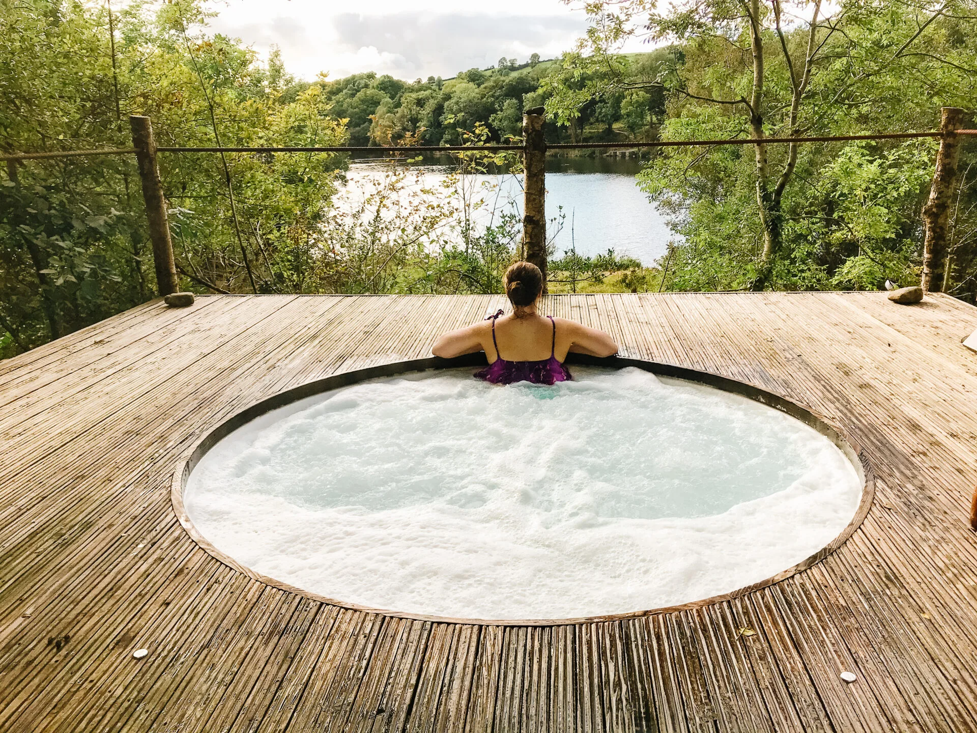 woman sits in a hot tub overlooking the view at finn lough resort
