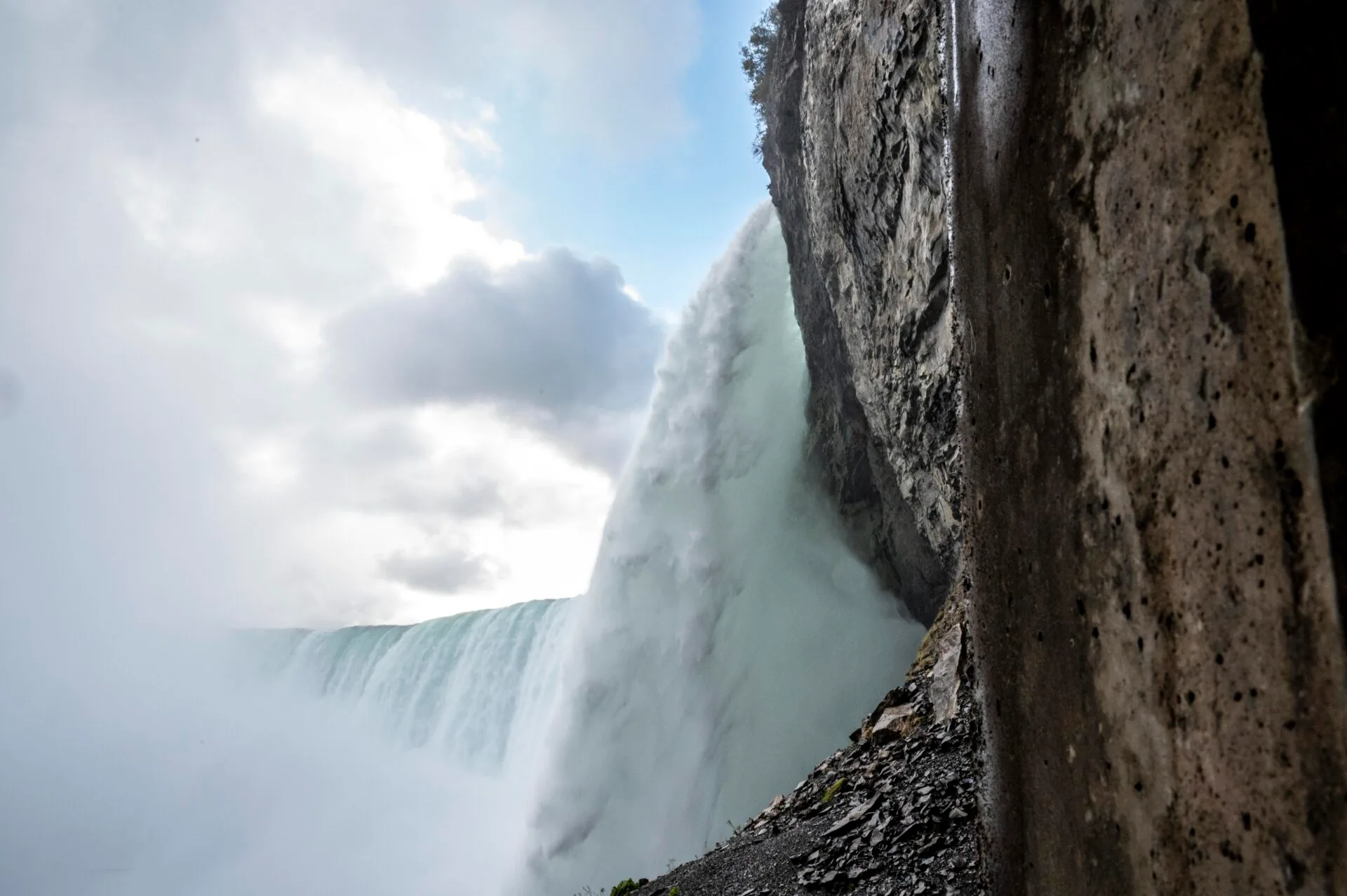view of Niagara Falls from below, the water rushes over the rock ledge