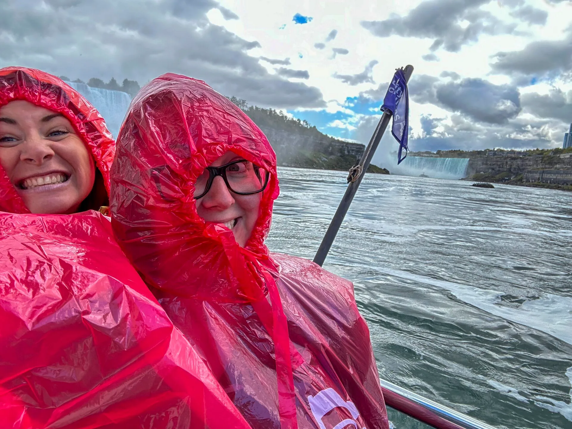 two woman wear red plastic ponchos in anticipation of going into the mist from niagara falls
