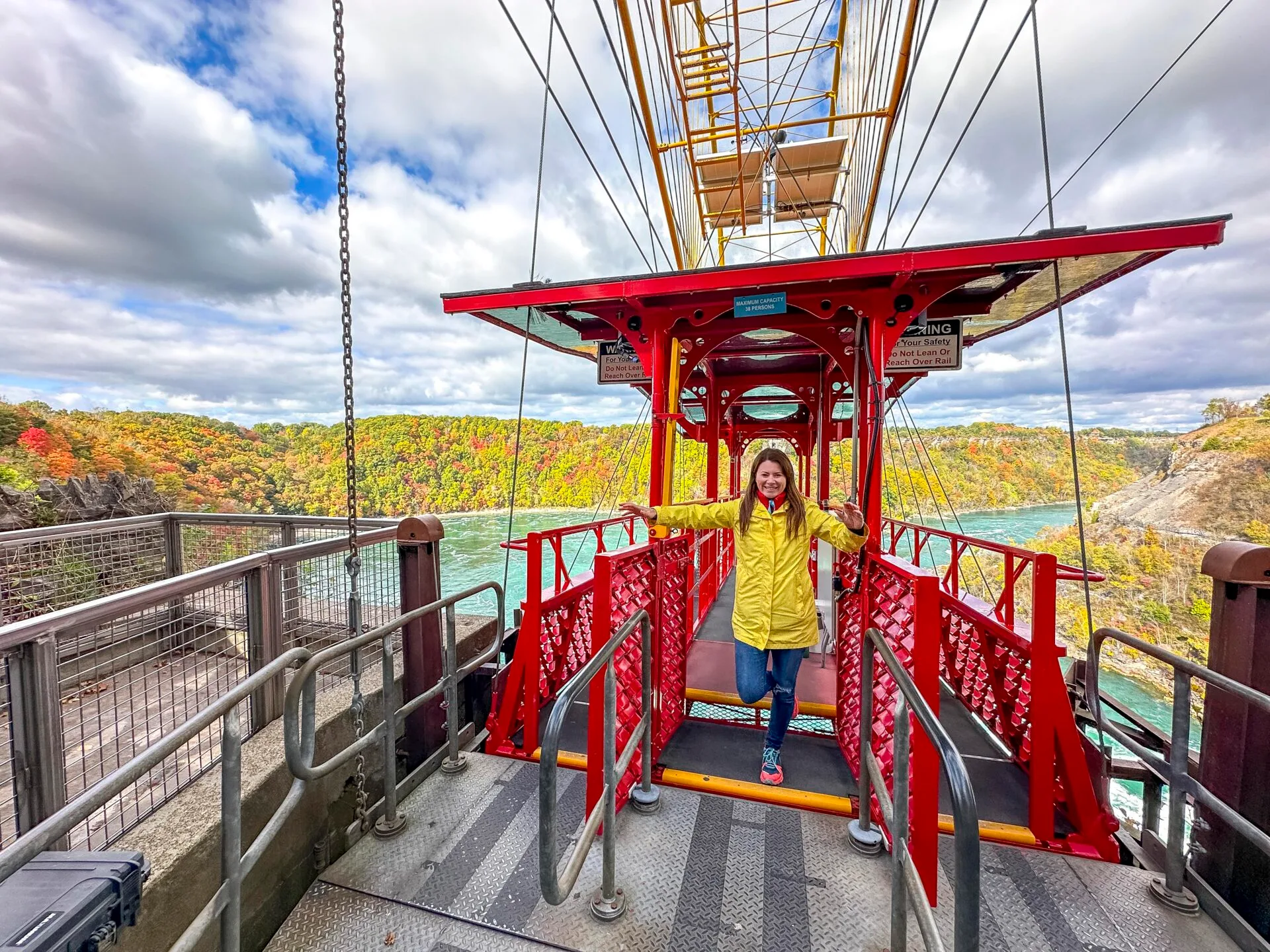 woman wearing a bright yellow raincoat stands on the edge of the whirlpool aero car in Niagara Falls in October