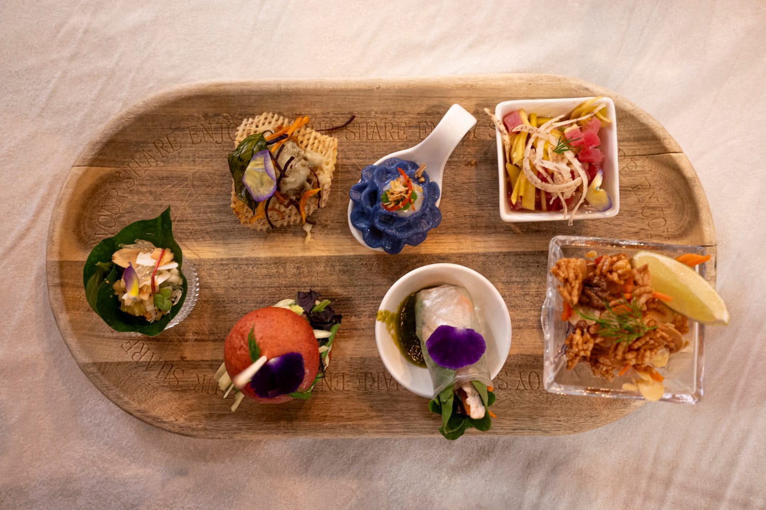 looking down at an oval wooden board that has multiple small dishes of thai food at food by fanta restaurant in langley city