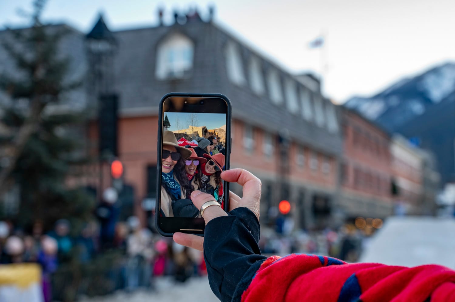 cell phone is being held out, taking a selfie of 3 women at skijoring banff